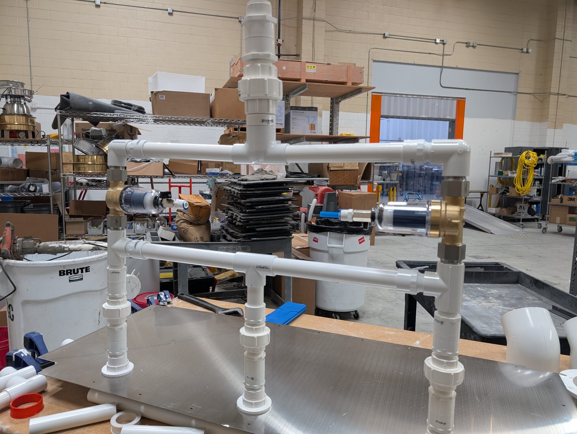 The two-tier PVC manifold with brass filter housings on the warehouse bench