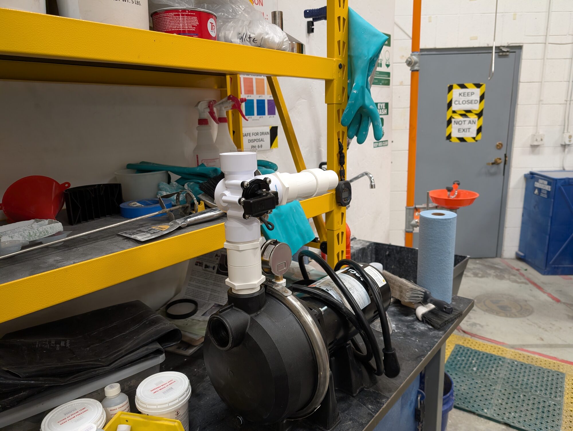The pump on a bench shelf with its PVC discharge tee and valve fitted