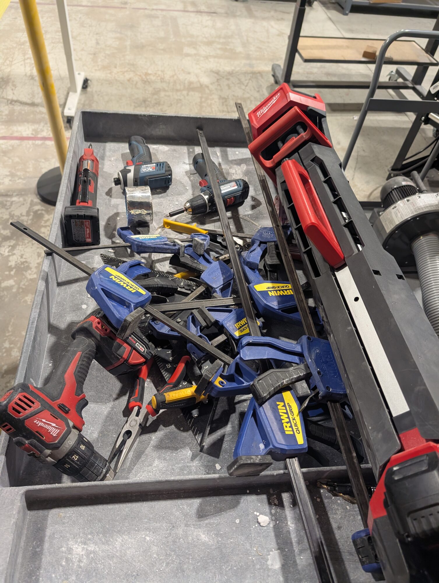 A cart of bar clamps, drills and lengths of punch stock