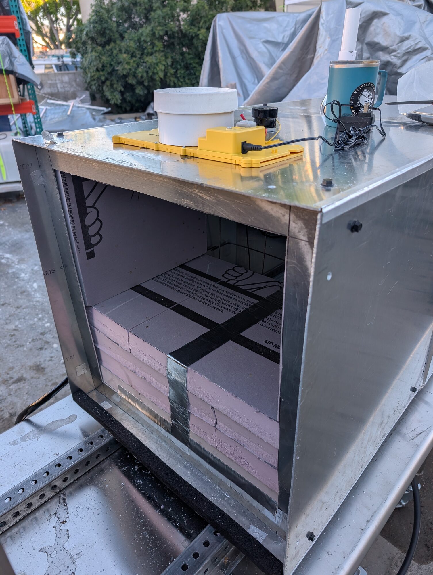 A white sample cup and a yellow actuator box mounted on top of an open cube