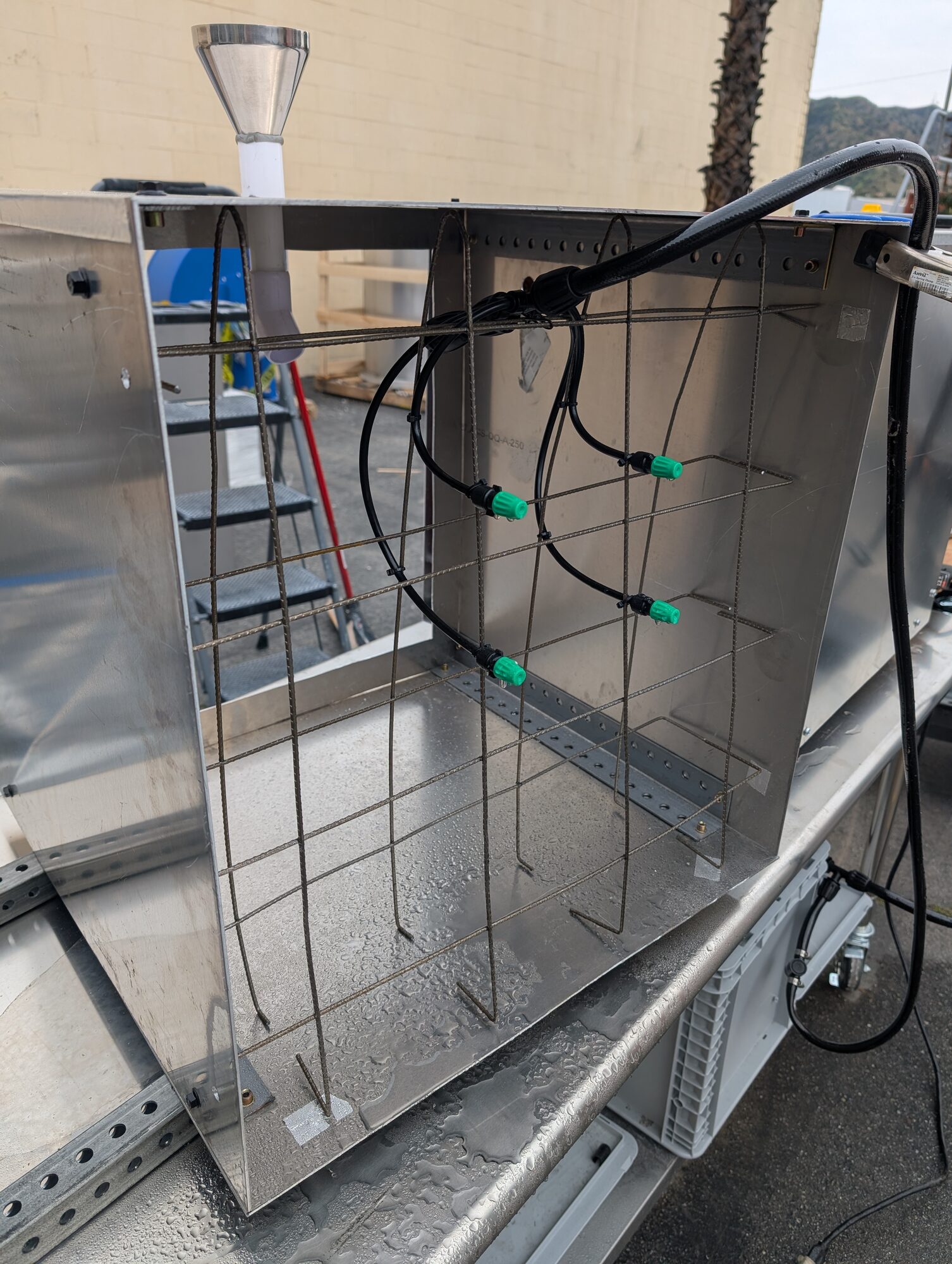 A rack of misting nozzles on a wire grid inside the housing