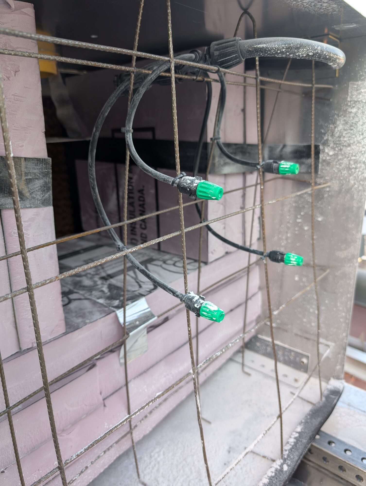 Close-up of green misting nozzles on black line tied to a rebar grid